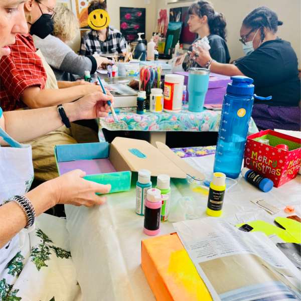 A table of multiple people working on art, brightly lit and colorful.